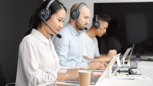 Support team with headsets working on laptops in an office