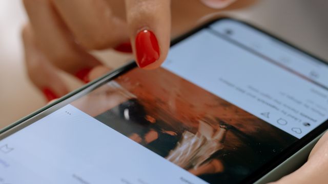 Close-up of a hand scrolling a social media feed on a smartphone