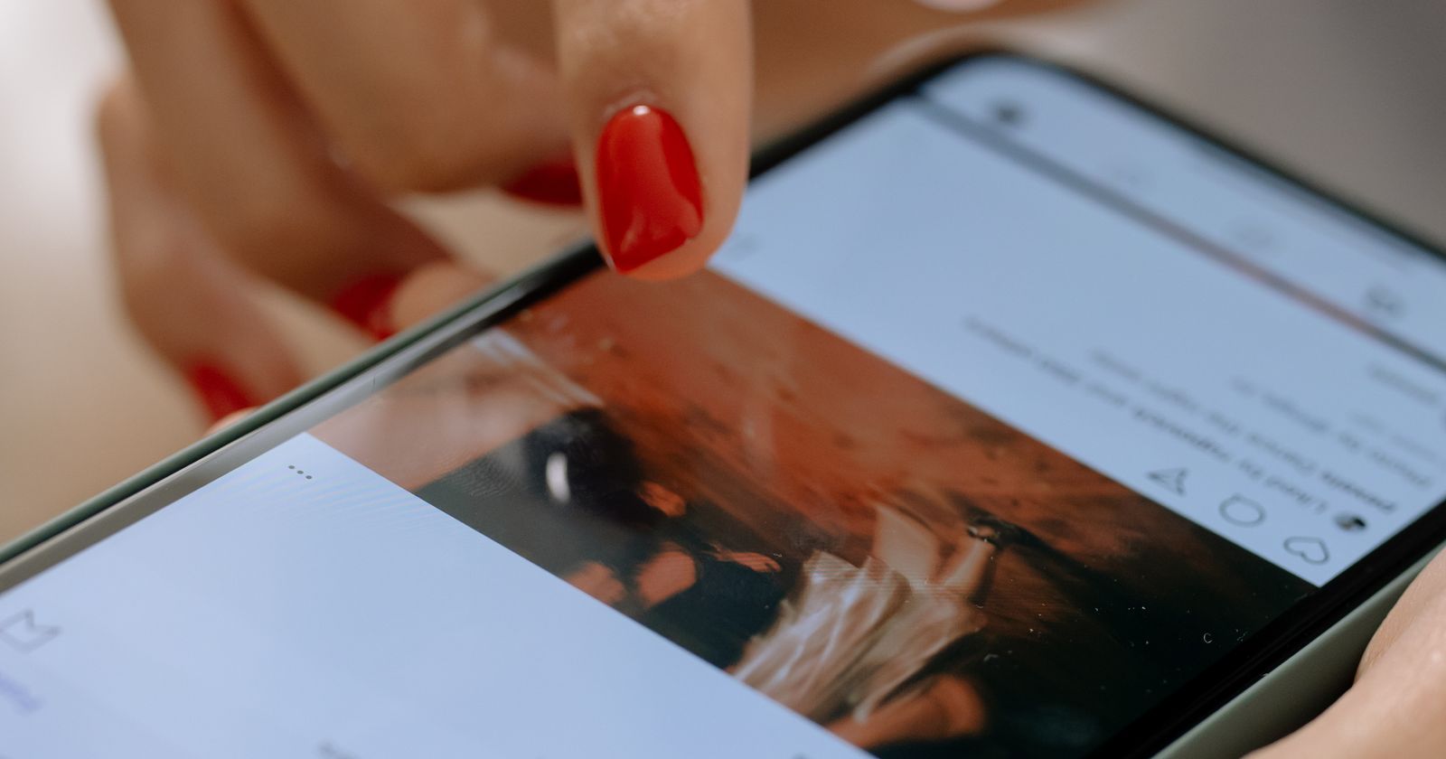 Close-up of a hand scrolling a social media feed on a smartphone